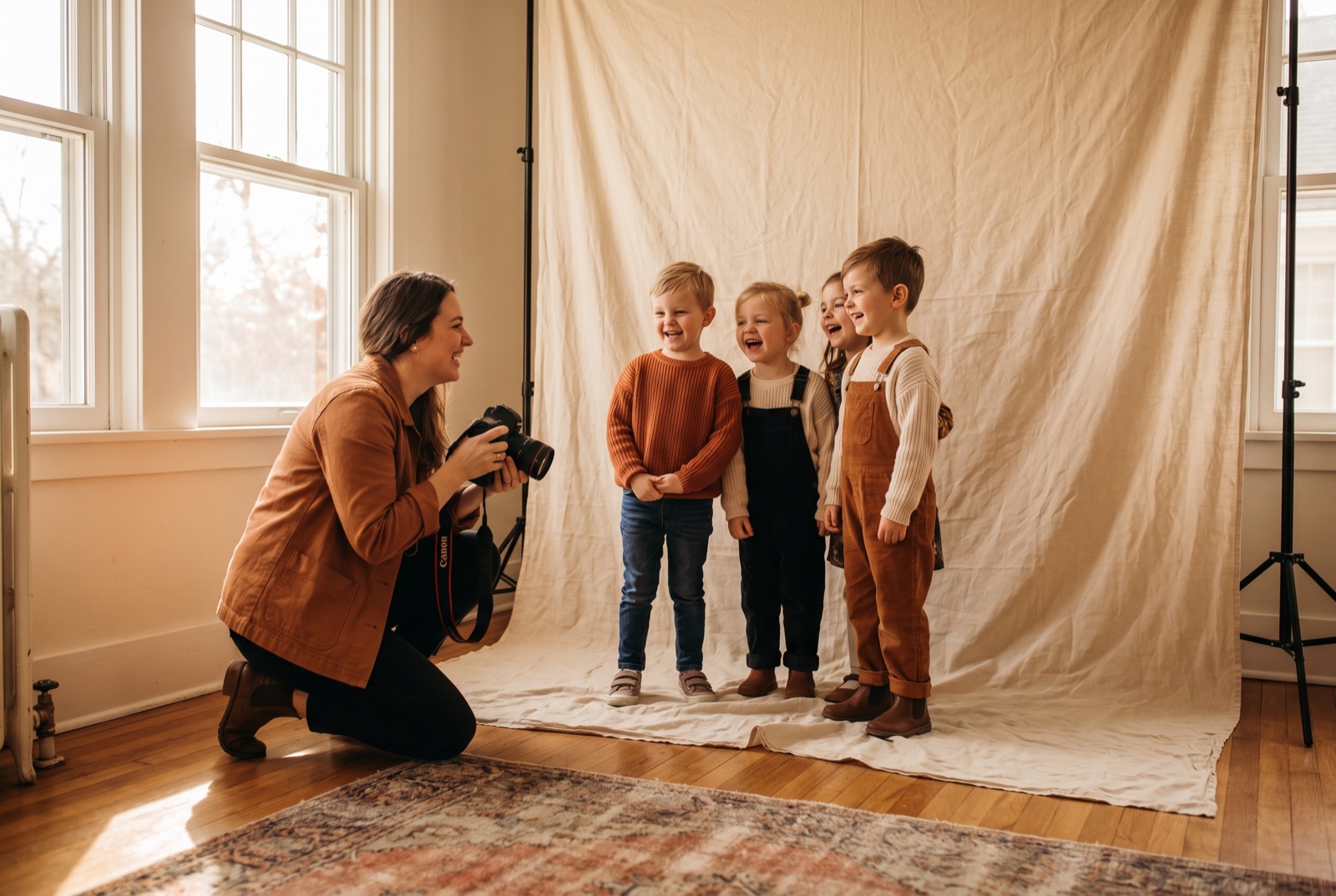 Fotografin fotografiert eine Gruppe lachender Kindergartenkinder vor hellem Stoffhintergrund